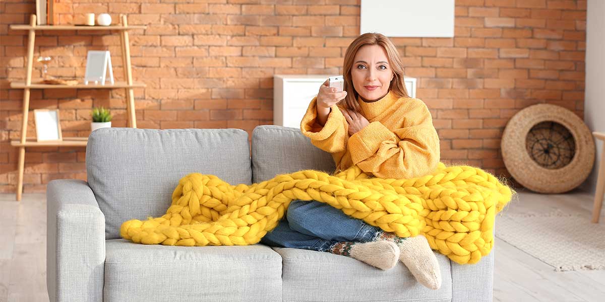 woman sitting on couch with knitted blanket