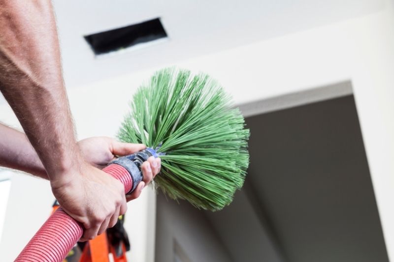 Technician using a rotary brush tool for residential air duct cleaning